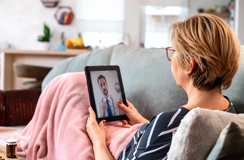Female patient attending virtual appointment on ipad with male physician